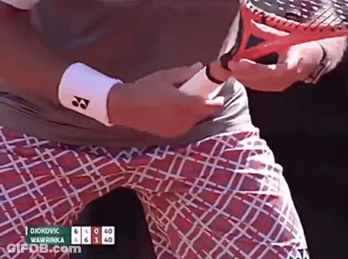 A Tennis Player Named Djokovic Is Holding A Tennis Racquet In His Hand GIF