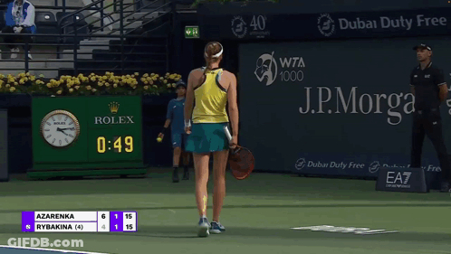 A Tennis Player Stands On A Court With A Rolex Clock In The Background GIF