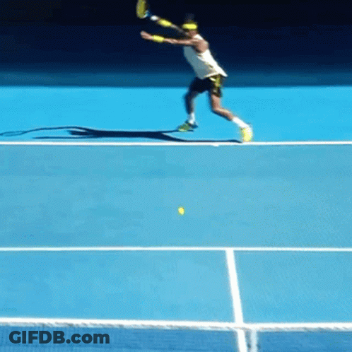 A Tennis Player Swings A Racket At A Yellow Ball On A Blue Court GIF
