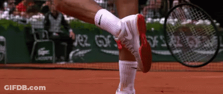 A Tennis Player Wearing Nike Socks Is Holding A Tennis Racquet On A Court GIF