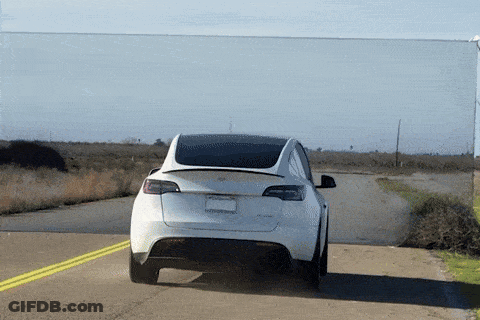 A Tesla Model Y Is Driving Down A Road GIF