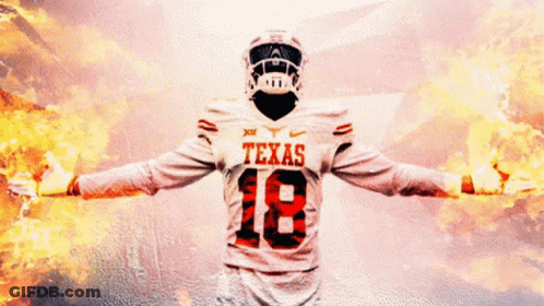 A Texas Football Player With His Arms Outstretched In Front Of A Fire Background GIF