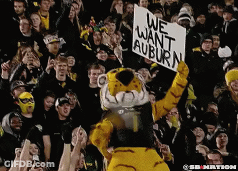 A Tiger Mascot Is Holding Up A Sign That Says We Want Auburn GIF