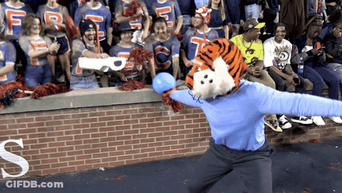 A Tiger Mascot Throws A Blue Ball In Front Of A Crowd With A Letter S In The Background GIF