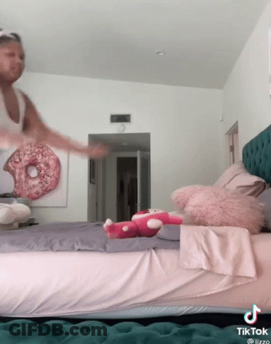 A Tiktok Video Of A Girl Jumping On A Bed With A Donut On The Wall Behind Her GIF