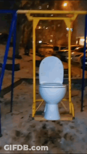 A Toilet On A Swing In A Playground At Night GIF