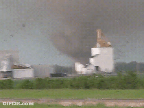 A Tornado Is Coming Towards A Building With Smoke Coming Out Of It GIF