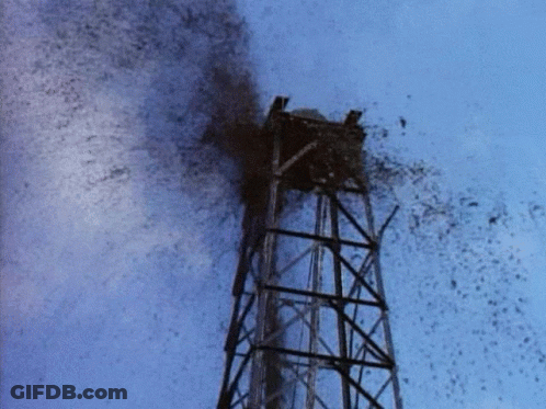 A Tower With A Blue Sky Behind It And A Lot Of Smoke Coming Out Of It GIF