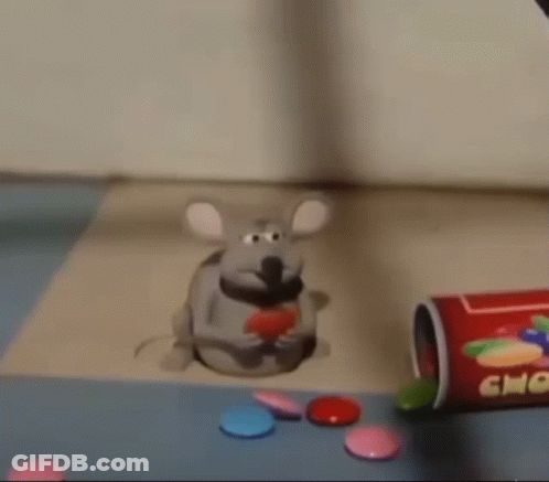 A Toy Mouse Is Sitting On A Table Next To A Bottle Of Candy . GIF