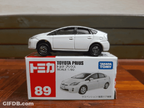 A Toy Toyota Prius Is Sitting On Top Of A Takara Tomy Box GIF