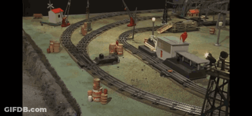 A Toy Train Set With Barrels And A Building With The Number 1 GIF
