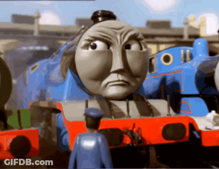 A Toy Train With A Very Angry Face And A Man In A Blue Uniform Standing Next To It GIF
