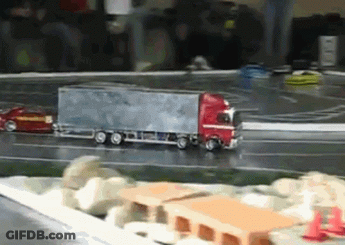 A Toy Truck Is Driving Down A Road Next To A Car GIF
