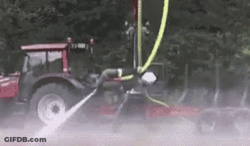 A Tractor With A Hose Attached To It Is Spraying Water On A Car . GIF