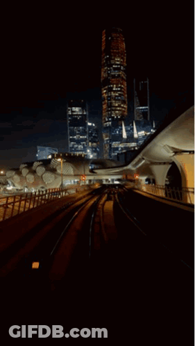 A Train Going Through A Tunnel At Night With A City In The Background GIF