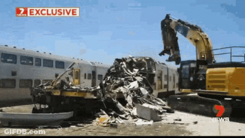 Demolition Of Train By Yellow Excavator With News Sign GIF