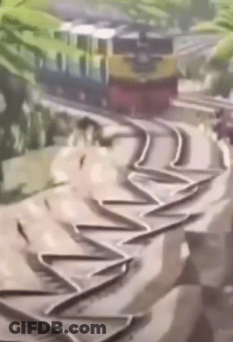 A Train Is Going Down A Curve On A Track . GIF