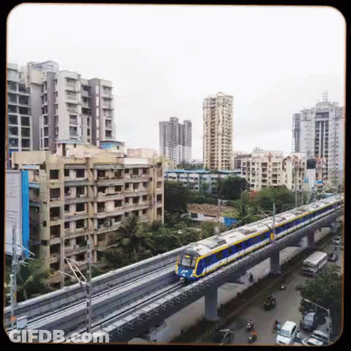 A Train Is Going Down A Track In A City With Buildings In The Background . GIF