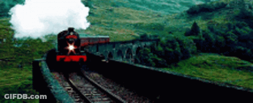 A Train Is Going Over A Bridge In The Mountains . GIF