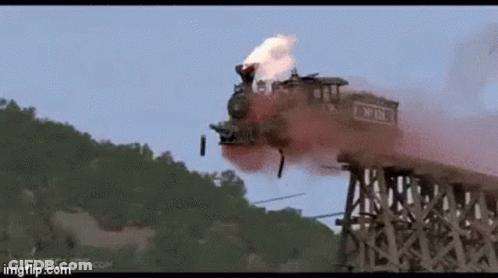 A Train Is Going Over A Wooden Bridge With Smoke Coming Out Of It GIF