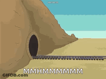 A Train Is Going Through A Tunnel In The Desert Next To A Mountain . GIF