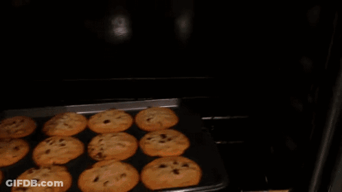 A Tray Of Chocolate Chip Cookies Being Taken Out Of An Oven GIF
