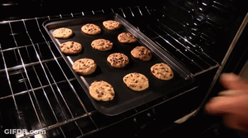 A Tray Of Chocolate Chip Cookies Is Being Pulled Out Of An Oven GIF