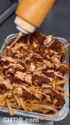 A Tray Of French Fries Is Being Poured With Ketchup GIF