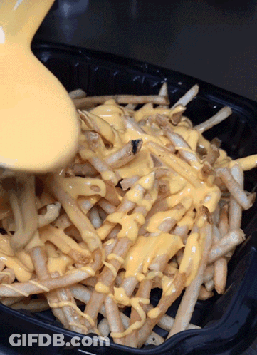 A Tray Of French Fries With Cheese Being Poured On Top GIF