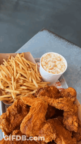 A Tray Of Fried Chicken Wings And French Fries With Coleslaw GIF