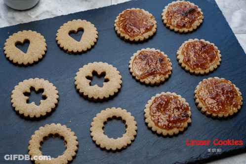 A Tray Of Linzer Cookies Sits On A Black Surface GIF