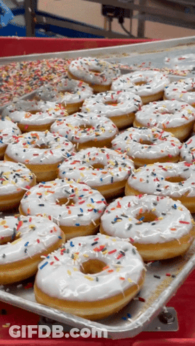 A Tray Of White Frosted Donuts With Sprinkles GIF