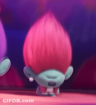 A Troll With Pink Hair And A Blue Face Is Standing On A Table . GIF