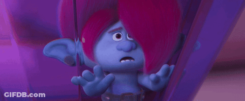 A Troll With Pink Hair And Blue Ears Is Sitting In A Purple Room . GIF