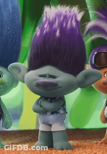 A Troll With Purple Hair Is Standing With His Arms Folded GIF