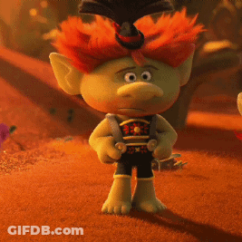 A Troll With Red Hair And A Top Hat Is Standing In The Desert GIF