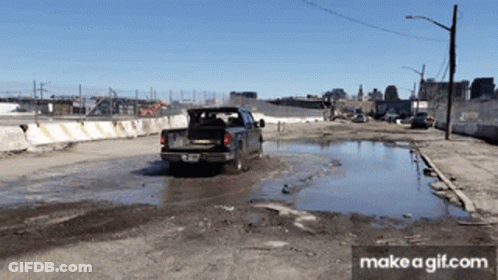 A Truck Is Driving Through A Muddy Puddle With Make A Gif.com At The Bottom Of The Screen GIF