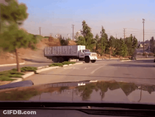 A Truck With A Fence On The Back Is Driving Down The Road GIF