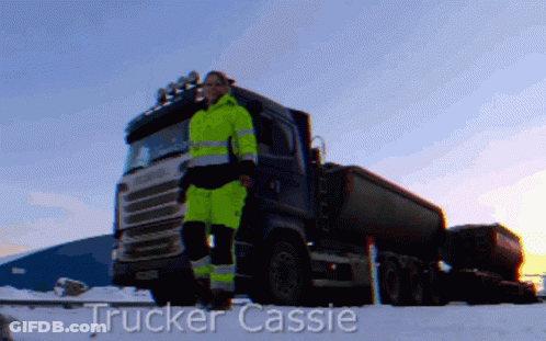 A Trucker Cassie Is Standing In Front Of A Truck In The Snow GIF
