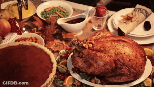 A Turkey Is Sitting On A Plate On A Table Surrounded By Plates Of Food GIF