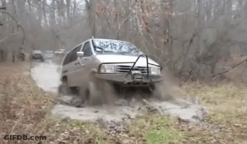 A Van Is Driving Through A Muddy Area With Trees In The Background GIF