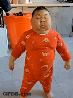 A Very Fat Baby In A Red Pajamas Is Standing On A Tiled Floor In A Kitchen . GIF