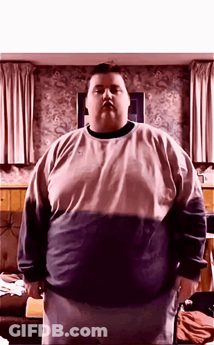 A Very Fat Man Standing In Front Of A Wall With Curtains GIF