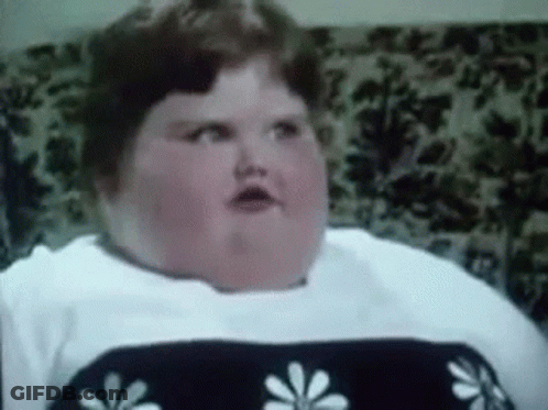 A Very Fat Woman Is Sitting On A Couch With A Floral Blanket On It . GIF