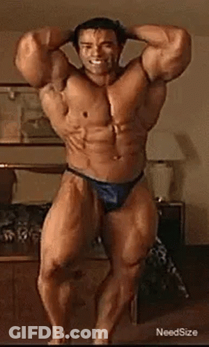 A Very Muscular Man In A Blue Thong Is Standing In A Room . GIF