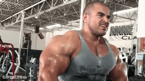 A Very Muscular Man Is Lifting Weights In A Gym Wearing A Tank Top That Says House Of Bodybuilding . GIF