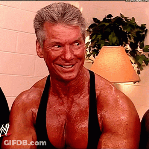 A Very Muscular Man Is Smiling And Wearing A Black Tank Top With The Letters N On It GIF