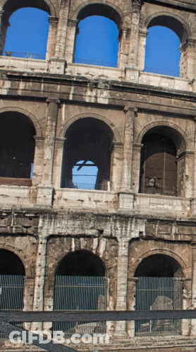 A Very Old Building With Arches And A Blue Sky Behind It GIF