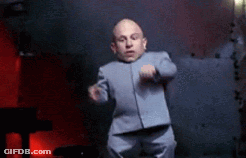 A Very Small Man In A Suit Is Dancing In Front Of A Piano . GIF