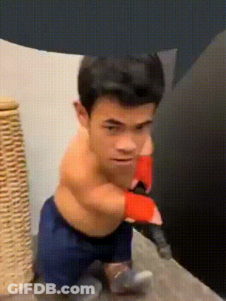 A Very Small Man Is Wearing Boxing Gloves And Sitting On A Bed GIF